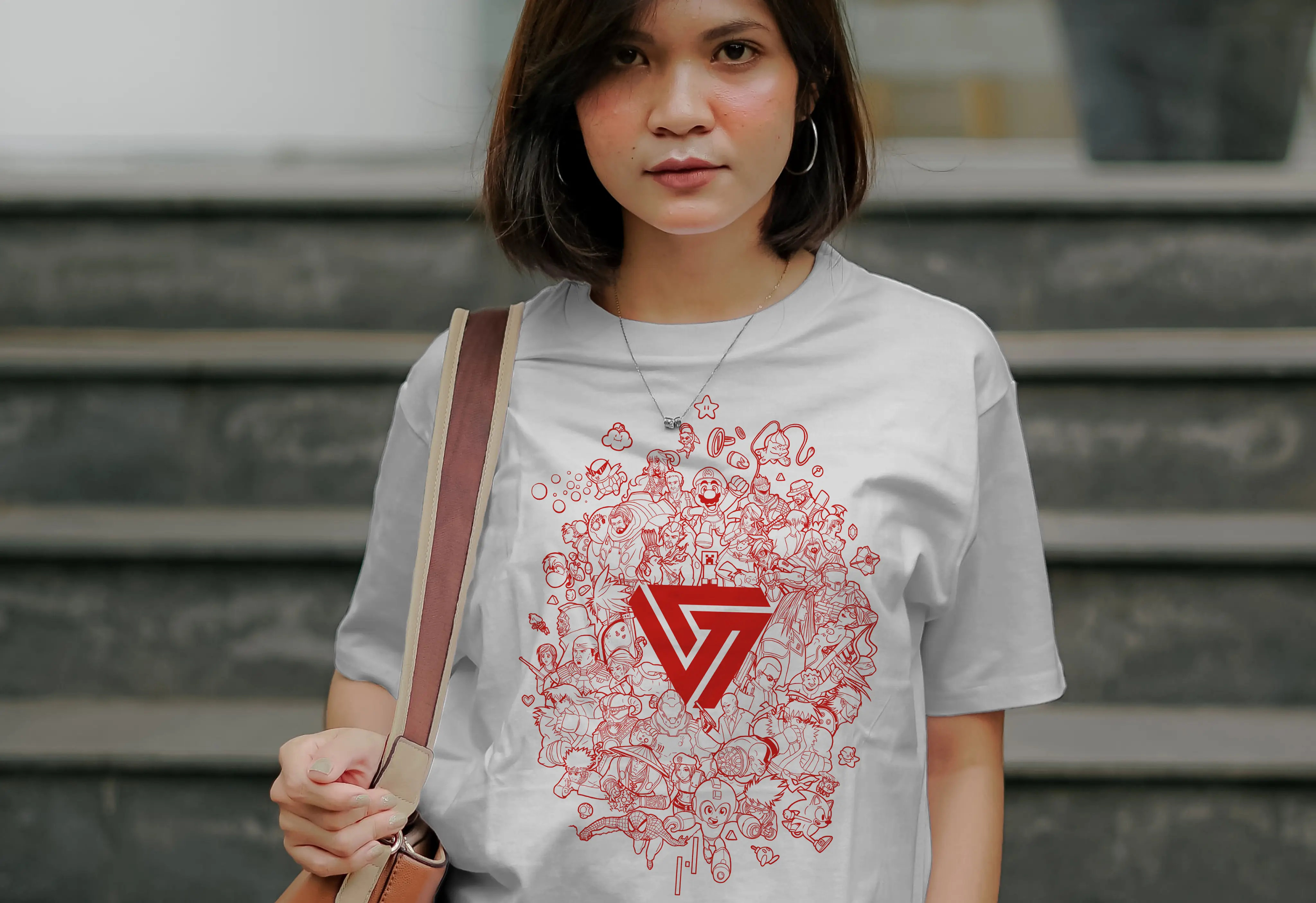 Photograph of a woman walking down a staircase wearing a white Versus t-shirt printed with an illustration created for Versus Podcast's 100th episode, featuring characters from Zelda, Minecraft, Gears of War, Mega Man, and Overwatch, with the Versus logo at the center.